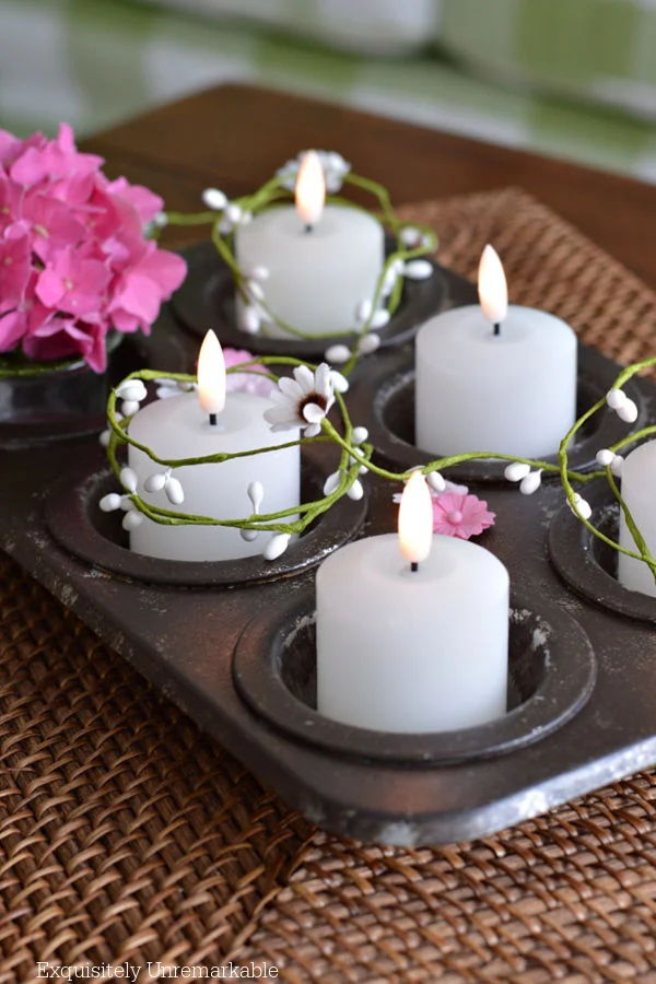 Dollar Tree Cupcake Tin Votive and Floral CenterpieceMakeover Dollar Tree Cupcake Tin Makeover with votives and flowers in each cup and garland wrapped around it